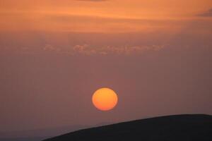 en solnedgång med moln och en orange Sol miljö i de himmel. foto