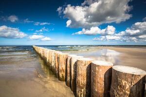 trä- vågbrytare på sandig leba strand i sent eftermiddag, baltic hav, polen foto