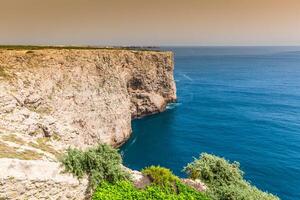 hög klippor och blå hav på cabo sao vicente på kust av portugal foto