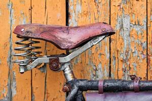 gammal cykel sittplats på de bakgrund av målad trä- plankor foto