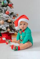 bebis i jul gnome kostym öppnas gåvor nära jul träd. Produkter för barn och högtider foto