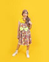 asiatisk hippie kvinna klänning i 80s årgång mode med färgrik retro Kläder medan Framställ isolerat på gul bakgrund för fint utrusta fest och pop- kultur begrepp foto