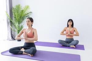 asiatisk kvinna som utövar yoga inomhus med enkel och enkel position för att kontrollera andning in och ut i meditationsställning foto