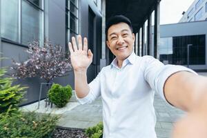 asiatisk studerande framställning selfie ser på telefon skärm och leende, ring upp med vänner foto
