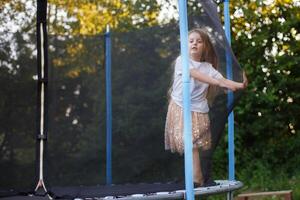liten barn flicka Hoppar på de trampolin i de tillbaka gård foto