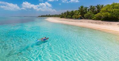 kaukasiska par turister snorklar i kristallklart turkost vatten nära ön Maldiverna. perfekta väderförhållanden på lyxresorts strandscen, lugnt havsvatten, par exotiskt vatten, undervattensvilda djur foto