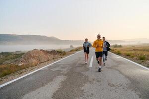 en grupp av vänner, idrottare, och joggare omfamning de tidigt morgon- timmar som de springa genom de dimmig gryning, energiserad förbi de stigande Sol och omgiven förbi de lugn skönhet av natur foto