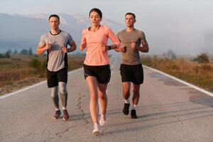 en grupp av vänner, idrottare, och joggare omfamning de tidigt morgon- timmar som de springa genom de dimmig gryning, energiserad förbi de stigande Sol och omgiven förbi de lugn skönhet av natur foto