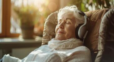äldre kvinna bär hörlurar i stol foto