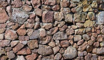 sten vägg bakgrund med mängd av rocks. ojämn och texturerad stenar med luckor foto