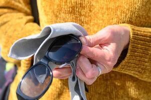 snyggt klädd ung kvinna våtservetter solglasögon med mikrofiber, närbild se, hög kvalitet Foto 5