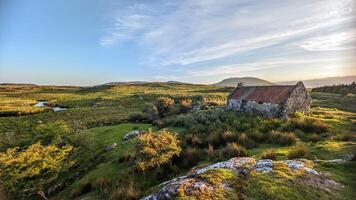 skön landskap landskap med gammal rostig tenn tak stuga på grön kulle på connemara nationell parkera i grevskap galway, irland foto