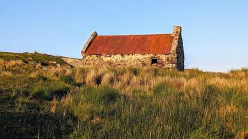 skön landskap landskap med gammal rostig tenn tak stuga på grön kulle på connemara nationell parkera i grevskap galway, irland foto