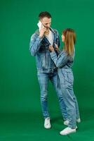 tigga knäböj se in i de ögon sträcka händer där önskan till dansa flicka inviterar en man till dansa på en grön bakgrund gör ögon denim kläder Chromakey föra tid med mig kärlek relation flirta foto