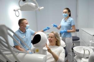 dental klinik mitten åldrig kvinna Sammanträde i stol med astronaut mjuk leksak leende Söt som visar barn den där dess säker till sitta rädsla av tandvård barn sjuksköterska lämnandet glasögon till läkare foto