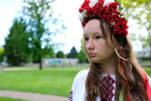 skön kvinna med en krans på en grön äng ukrainska flicka med en krans av blommor foto
