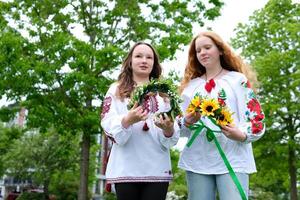 gammal ukrainska traditioner vävning kransar på ivan kupala två flickor med skön röd hår under vind är framställning för kväll solnedgång sjösättning skön blommig dekorationer broderad shirts foto