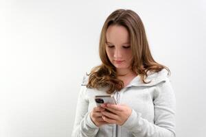 porträtt av spänd koncentrerad kvinna tonåring med mycket lång brun hår spelar spel på henne cell telefon varelse vinnare gestikulerar i glädje över vit bakgrund. begrepp av känslor foto