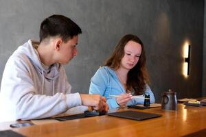 lunch eller lunch äter sushi i en restaurang Pojkar Tonårs flickor äter rullar på en trä- tabell mot en grå vägg bakgrund med ätpinnar kinesisk mat familj bror syster ungdom foto