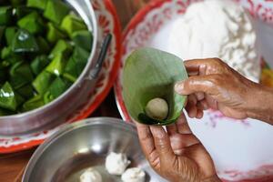 stänga upp händer håll banan blad till slå in deg bulle för matlagning thai traditionell efterrätt. begrepp, thai mat. på vilket sätt till laga mat, steg av matlagning. thai livsstil, förbereda mat för kulturell firande evenemang. foto