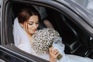 en brud är körning i en bil med en bukett av vit blommor foto