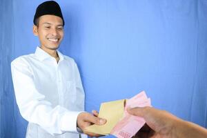leende uttryck av asiatisk muslim man ger pengar för portion, donation eller zakat foto