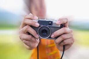 ung fotograf innehar årgång stil filma kamera i henne hand och inspekterar filma kamera för använda sig av efter filma kameror ha bli populär med fotografer i dag eftersom av deras unik bild toner. foto