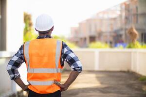 Bakom de scener förman bär reflekterande väst och hård hatt inspekterar konstruktion webbplats till säkerställa konstruktion möter teknik lagets design planer och för de skönhet och säkerhet av invånare. foto