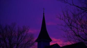 de översikt av en kyrka torn är markerad mot de djup purpur och blues av ett kväll himmel foto