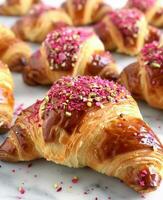 stänga upp av rosa glaserad croissanter med pistaschmandlar på vit marmor yta foto