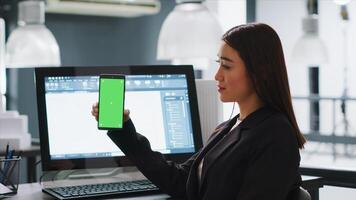 utvecklare visar mobil telefon med grönskärm mall, arbetssätt i små företag coworking Plats. ingenjör använder sig av isolerat copy layout på tom attrapp skärm, Chromakey bakgrund. foto