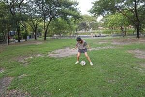 kvinna fotboll spelare öva använder sig av de boll i de parkera fält flitigt och lyckligt. foto