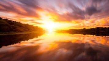 en solnedgång eller soluppgång scen över en sjö eller flod med dramatisk molnig himmel reflekterande i de vatten på en sommar kväll eller morgon. foto