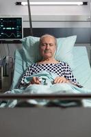 porträtt av senior man patient vilar i sjukhussäng foto