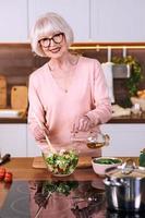 senior glad kvinna lagar mat på modernt kök. mat, färdigheter, livsstilskoncept