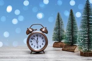 jul bakgrund med små julgranar och vintage väckarklocka på en trä bakgrund med ljus. stänga