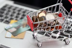 vagn med mynt och kreditkort på dator, idé för shopping och onlinebetalning med som affärsbakgrund foto