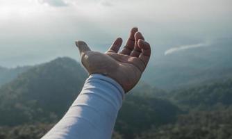 händerna utsträckta för att ta emot naturligt ljus och utsikt över bergen foto