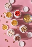många färg piller kapslar vitaminer på rosa bakgrund. hälsotillskott och läkemedel
