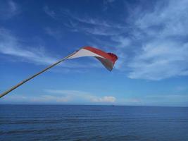 Indonesiens flagga vajar i vinden på kallad Sejarah Beach, Sumatra foto