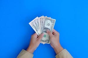 finans och bank representeras av en hand som håller en sedel med begreppet pengar på en blå bakgrund. foto