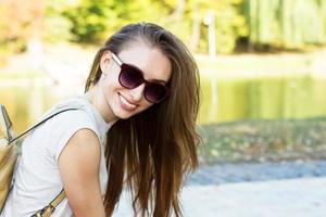närbild glad kvinna ler med perfekt leende och vita tänder i en park och tittar på kameran foto