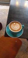 kaffemjölk med hjärtform i en blå kopp på bordet foto
