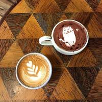 två kaffemjölk och choklad i en vit kopp på ett träbord foto