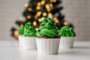 julgransformade cupcakes, omgivna av festliga dekorationer och ljus i bakgrunden foto