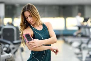 ung kvinna med smartphone stående i gymmet foto