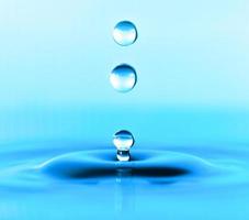 transparent vattendroppe stänk realistiskt och blått vatten färgat på vitt. foto