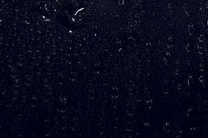 vattendroppar på svart bakgrund. abstrakta daggvattendroppar på ett fönsterglas för fotoöverlagringseffekt eller ger fräsch effekt på en mockup för drycker. makro skott av den detaljerade regndroppen. foto