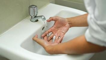 tvätta händerna i det vita handfatet för att hålla sin hand ren och steril. ta bort från vidhäftade bakterier. foto