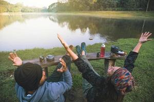 asiatiska par känner sig avslappnade och glada när de dricker morgonkaffe vid sjön. par romantisk resande camping, smekmånad. foto